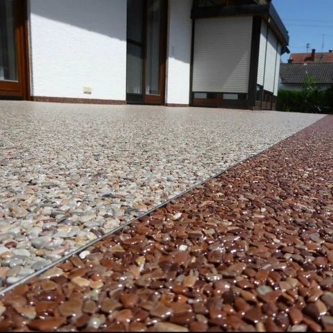 Terrasse mit hellem Steinteppich und Rand aus rotbraunem Marmorkies
