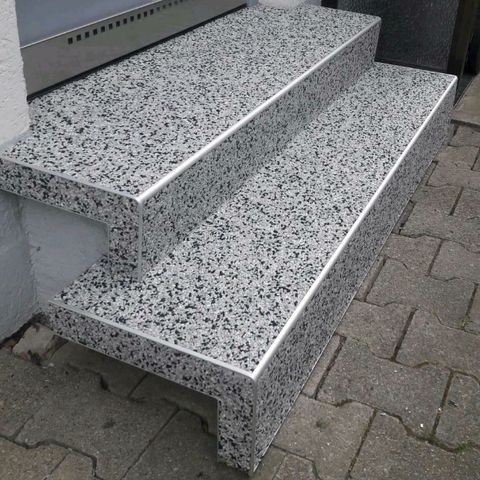 Sanierte Außentreppe mit grau-weißem Steinteppich und Kantenprofilen